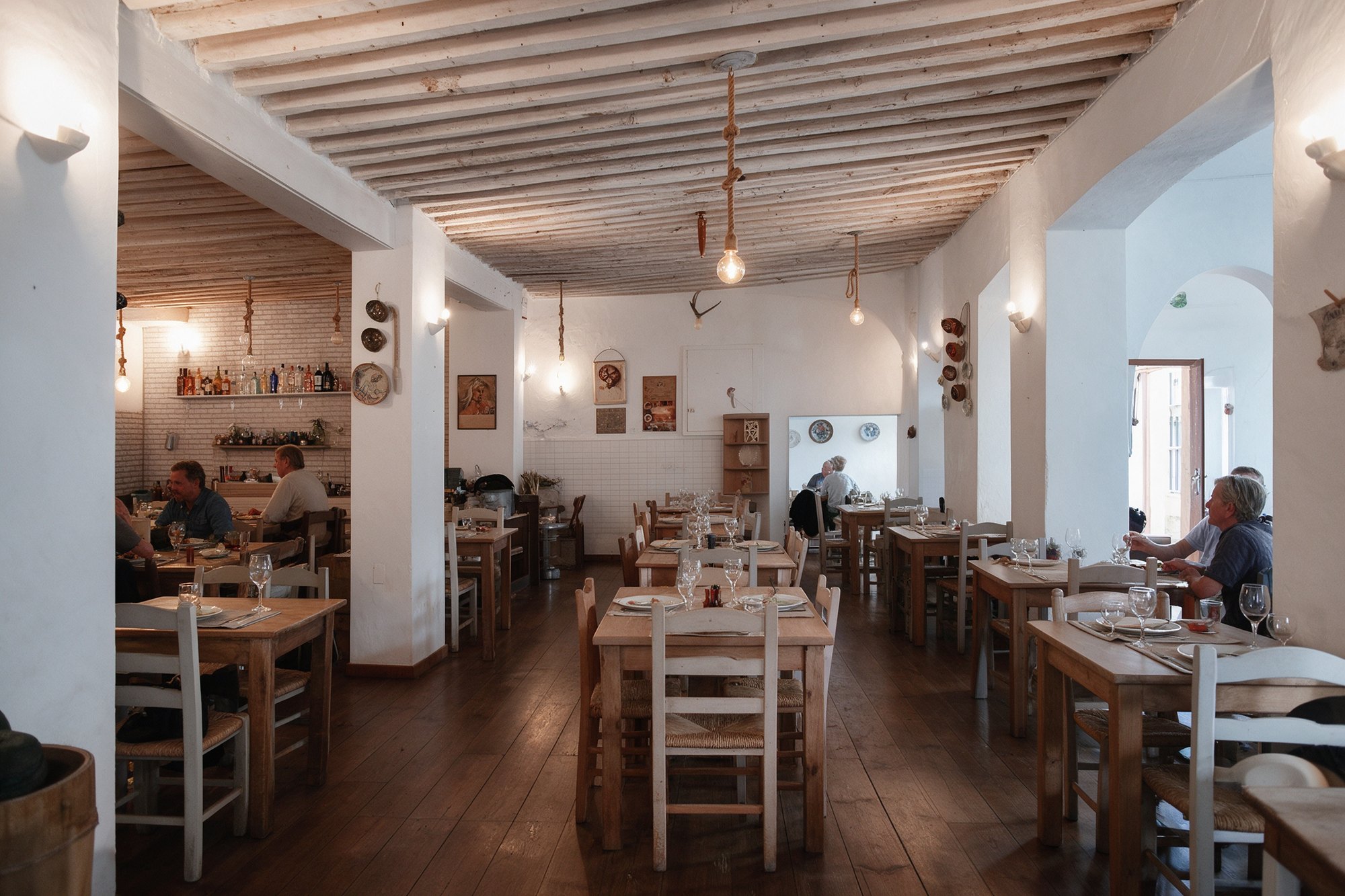 Comedor del restaurante con vigas de madera, mesas blancas y luz cálida